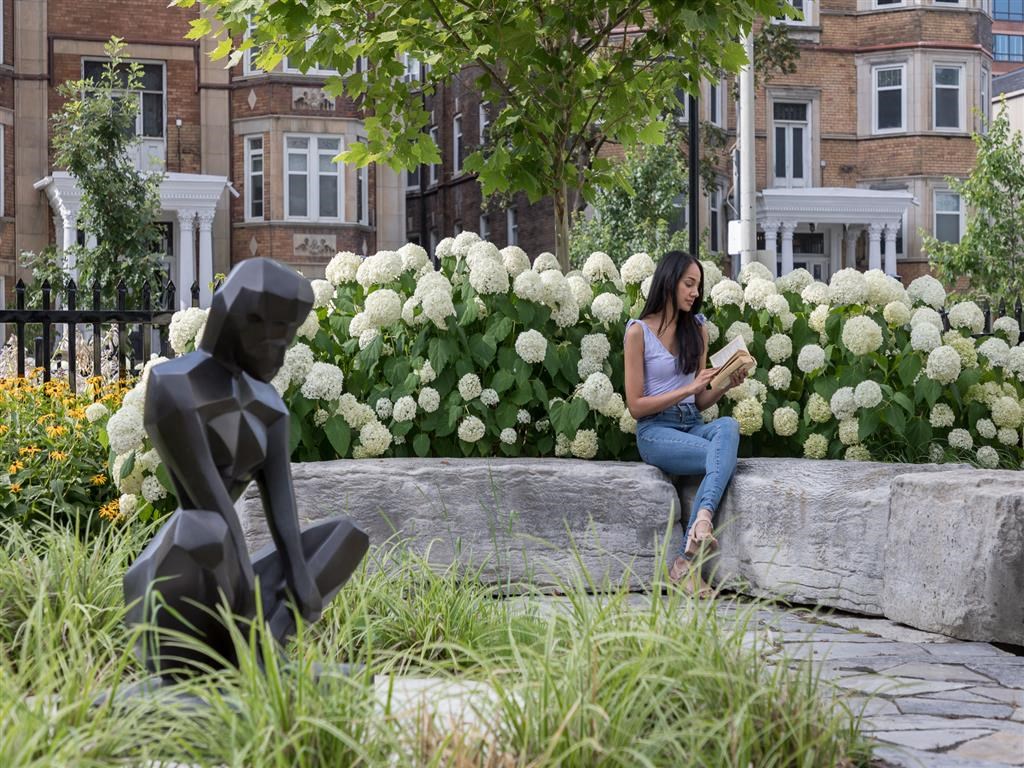 a woman sitting on a stone wall next to a statue