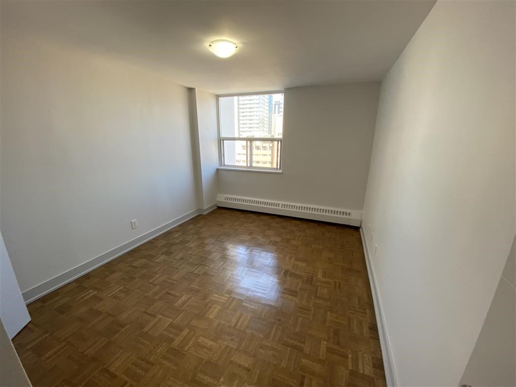 a empty living room with a window and wooden floors