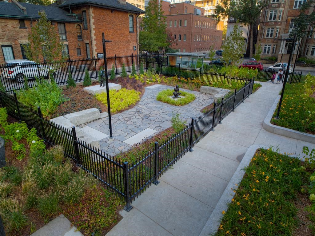 a garden with a sidewalk and a wrought iron fence