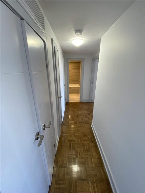 a hallway with white walls and a wooden floor