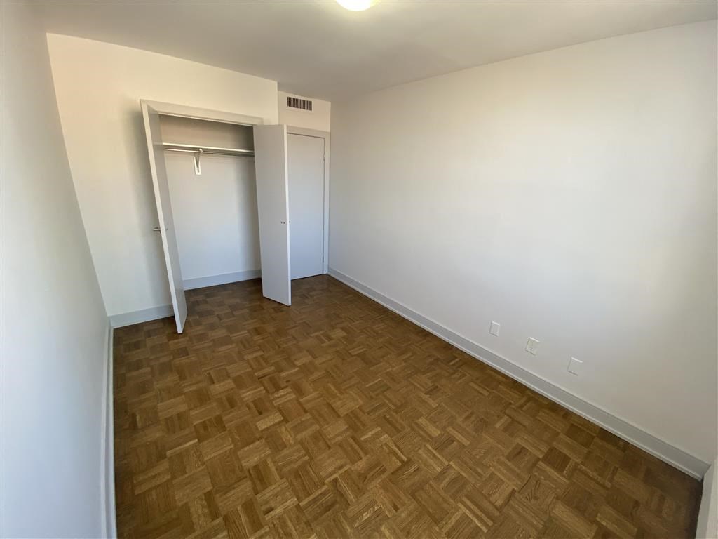 an empty room with a wooden floor and a closet