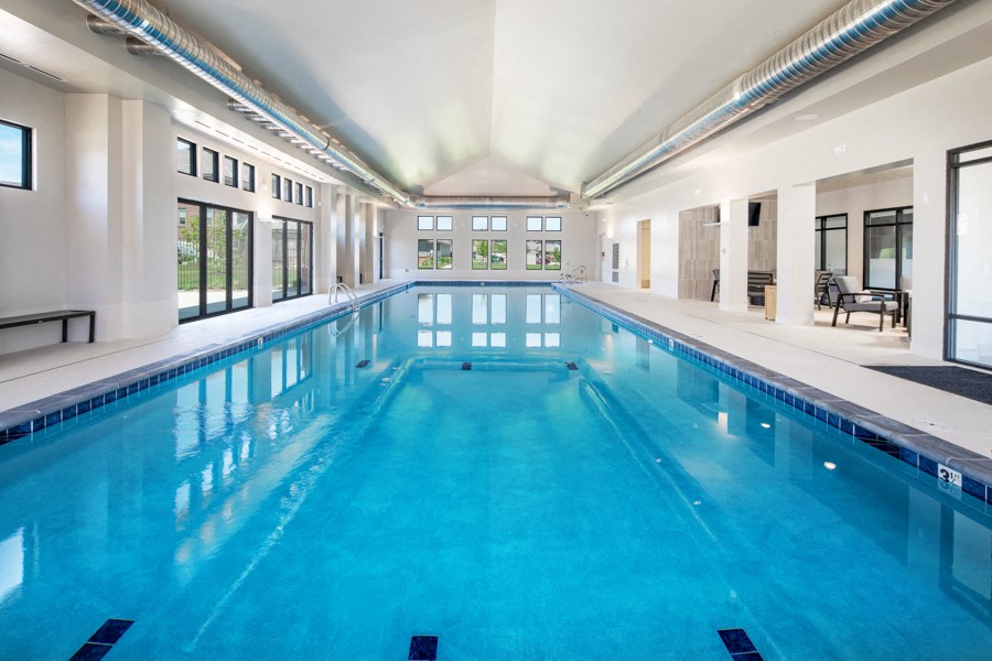 A large indoor swimming pool with a sunny day outside.