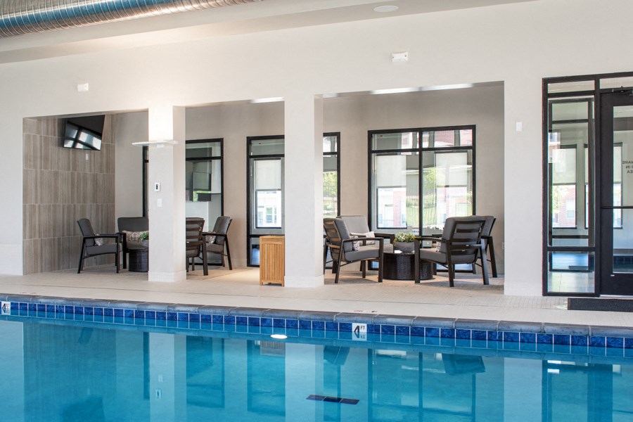 A swimming pool in a room with a table and chairs.