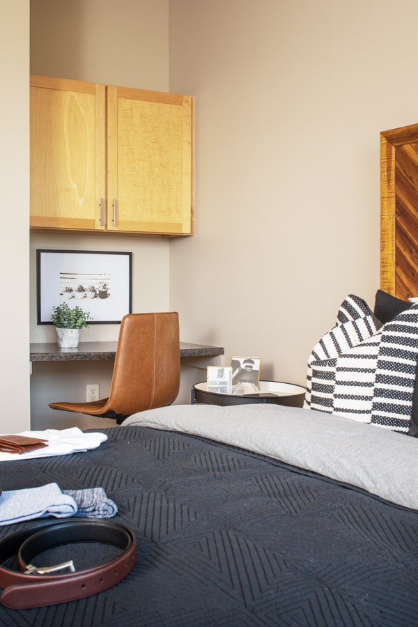 A bedroom with a bed, chair, and a picture on the wall.