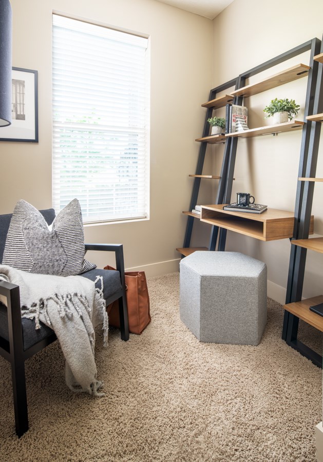 A living room with a grey sofa and a wooden shelf.