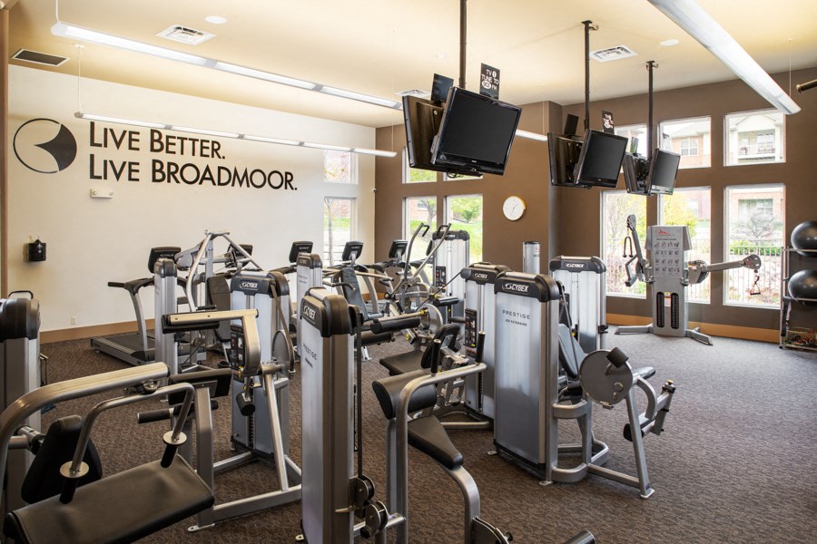 A gym with a variety of equipment including treadmills, weights, and exercise machines.