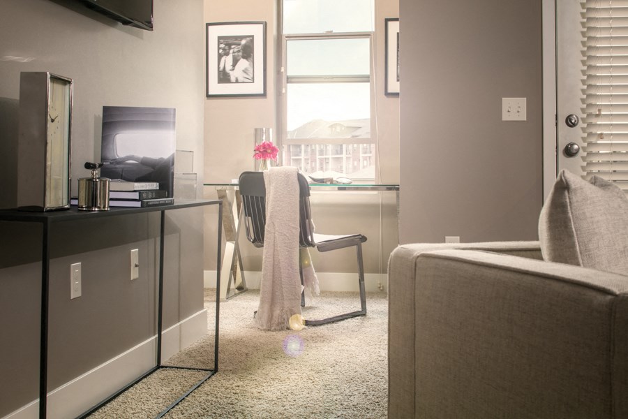 A living room with a grey couch and a chair with a grey blanket draped over it.