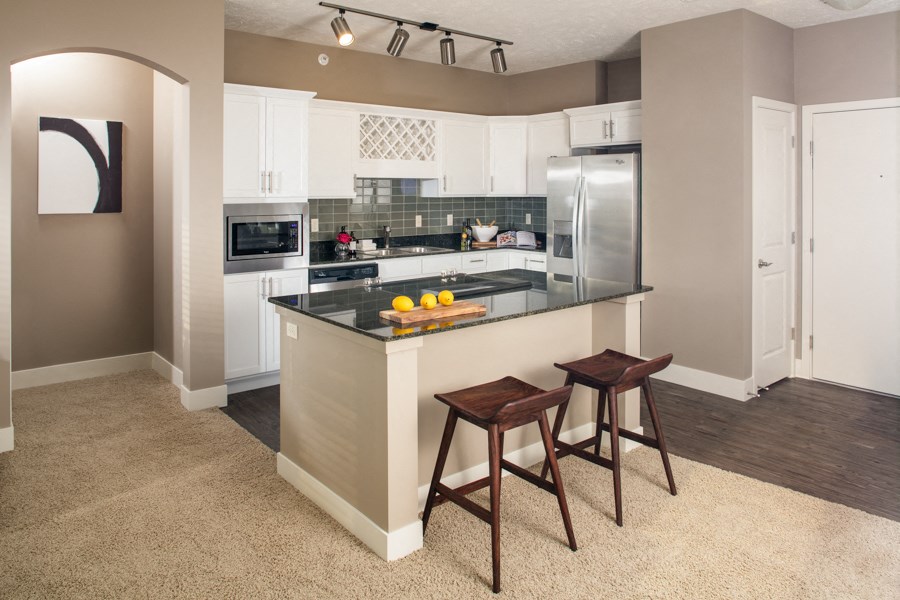 A kitchen with a bar stool in front of the island.