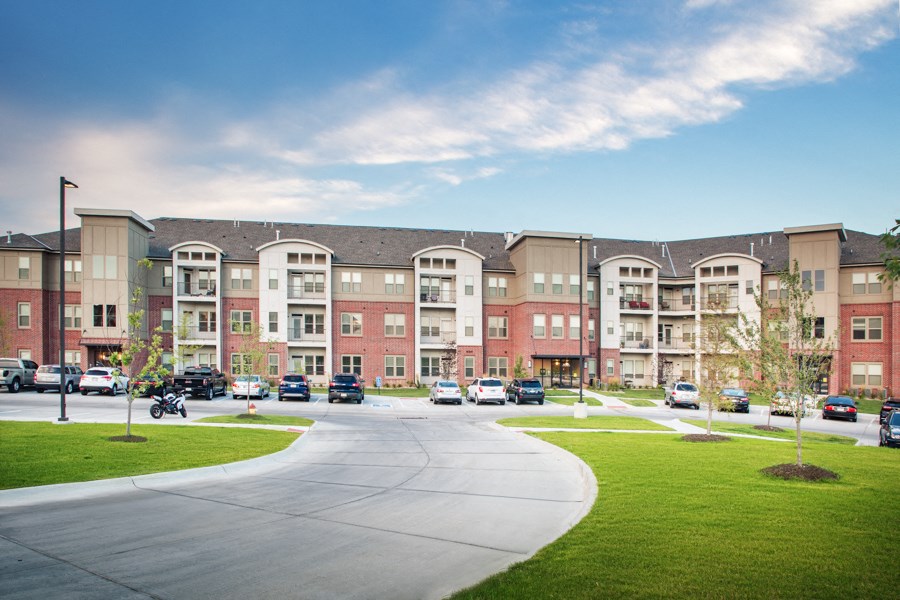 A large apartment complex with a parking lot in front.