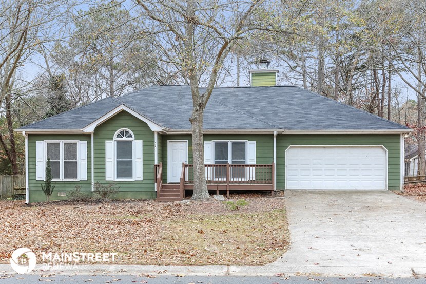 a green house with a porch and a white garage door