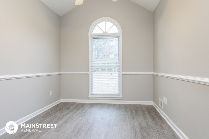 an empty room with wood floors and a large window