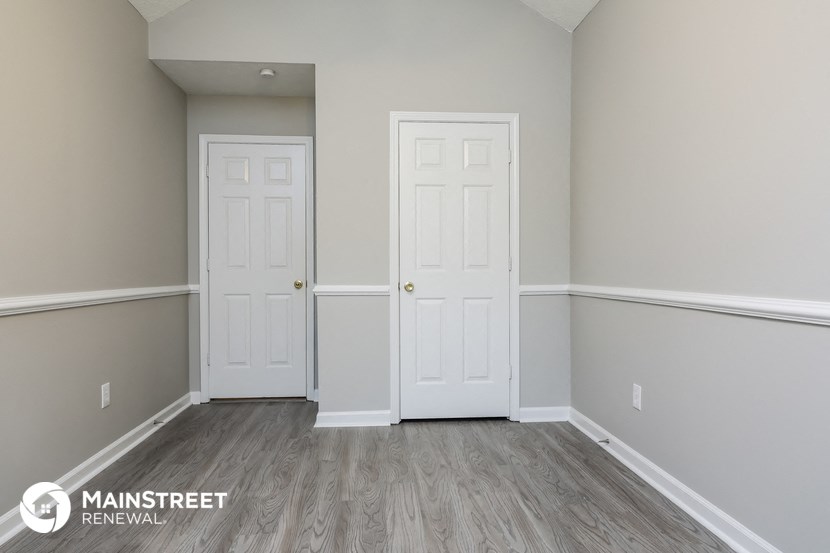 a bedroom with two doors and a wooden floor and grey walls