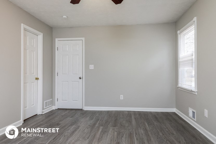 the living room of a renovated house with wood floors and a white door