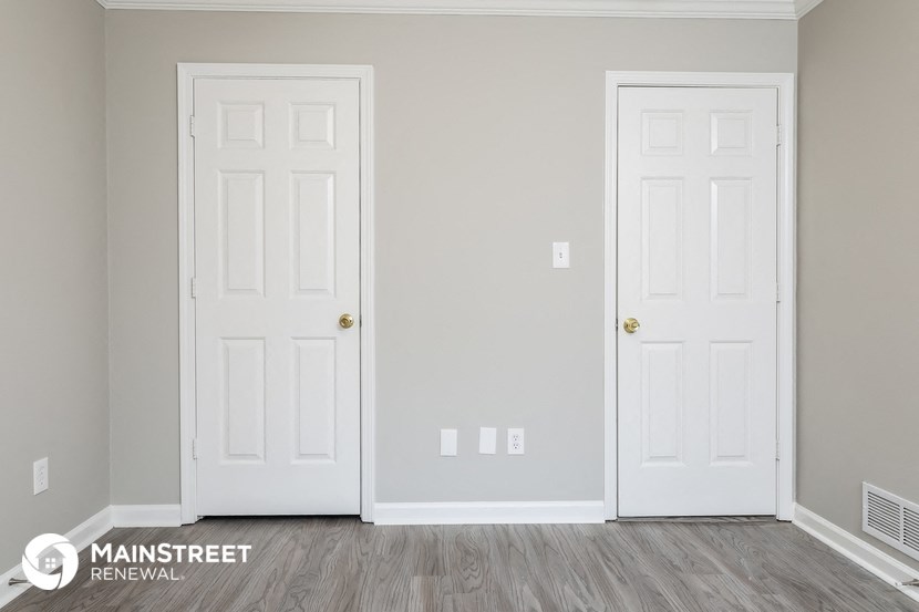 a room with two white doors and a wood floor    and a closet