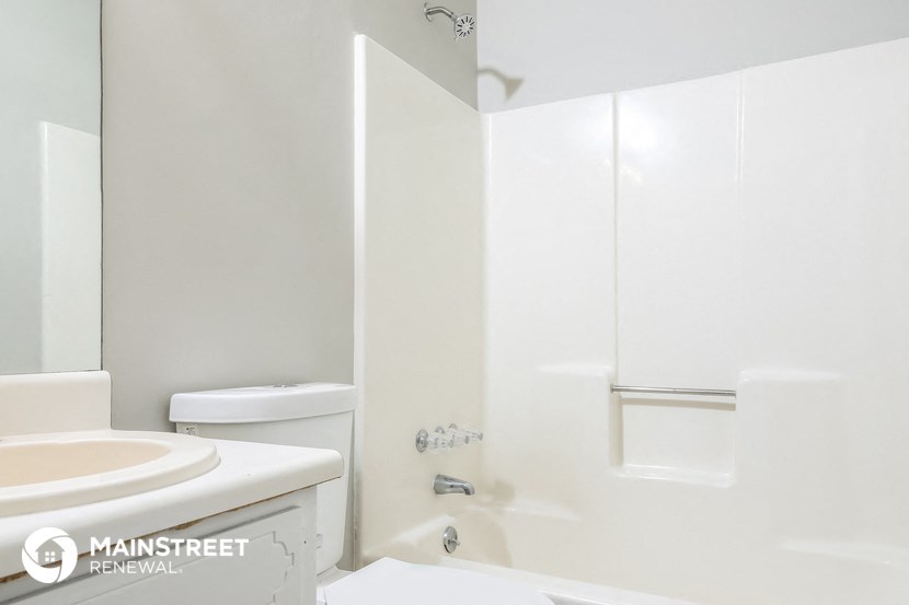 a white bathroom with a shower and toilet and a sink