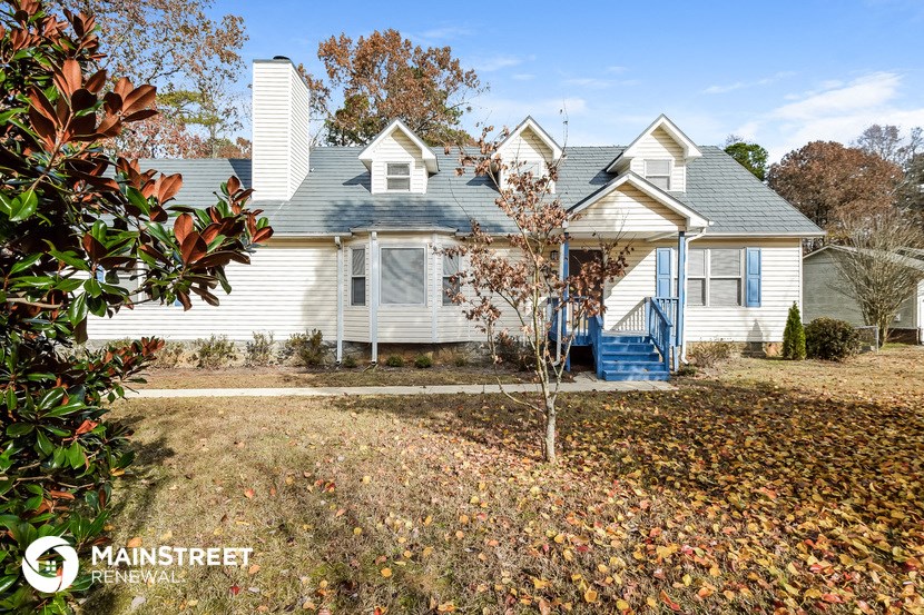 a white house with a blue roof and a yard with fallen leaves