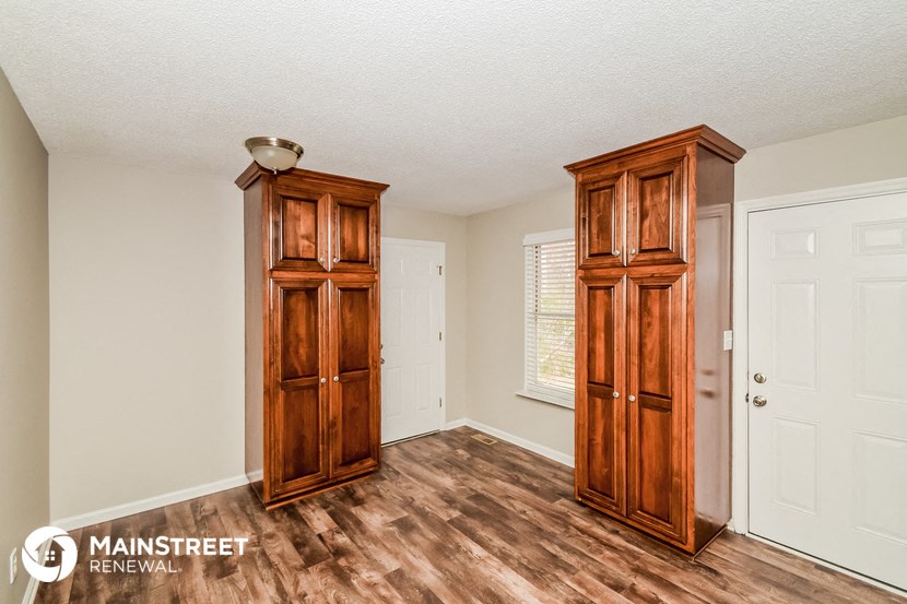 the living room of a house with wooden floors and wooden cabinets