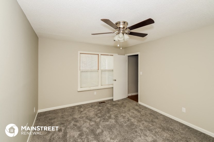 the spacious living room with ceiling fan and carpet