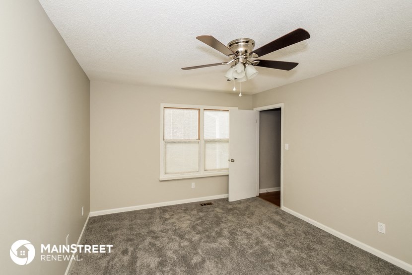 the spacious living room with ceiling fan and carpet