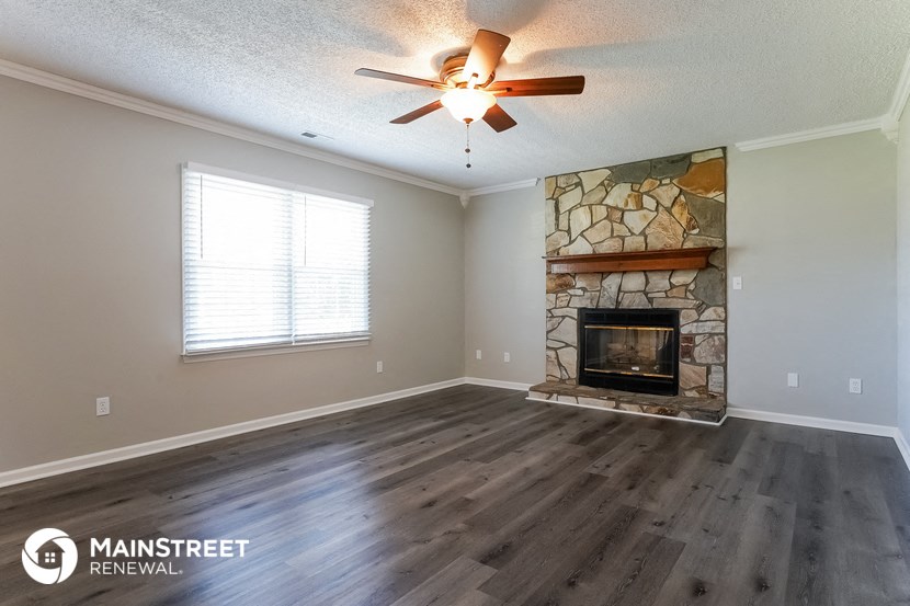 the living room has a stone fireplace and hardwood floors