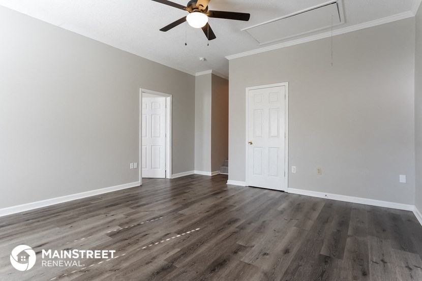 the living room of a new home with wood flooring and a ceiling fan