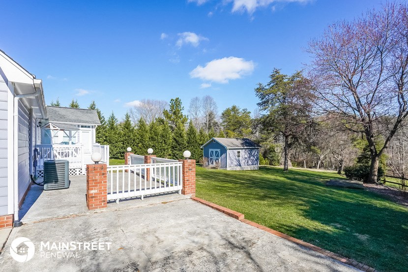 a backyard with a white fence and a house and a blue shed