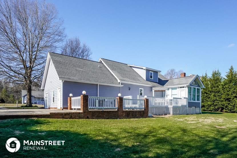 a blue and white house with a porch and a lawn