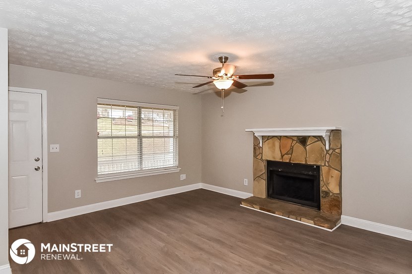 the living room has a fireplace and a ceiling fan
