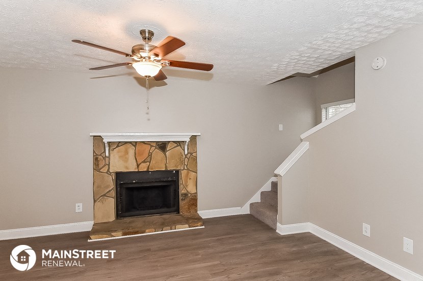 the living room with the fireplace and ceiling fan