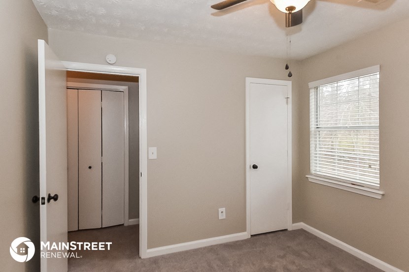 the interior of a bedroom with a closet and a ceiling fan