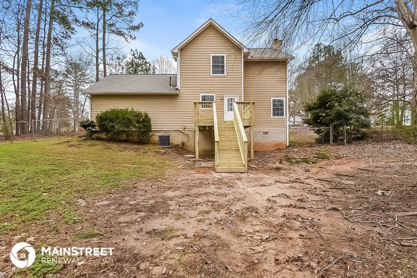 the front of a house with stairs and a dirt driveway
