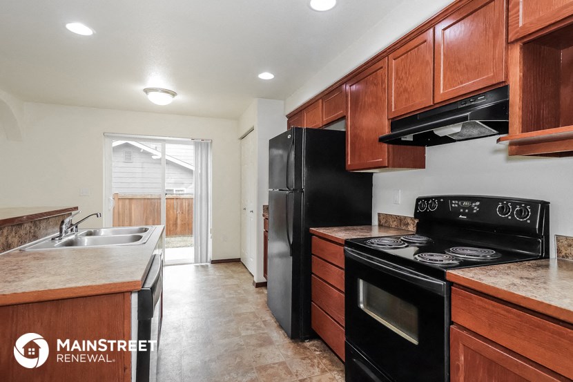 a kitchen with black appliances and wooden cabinets and a black refrigerator