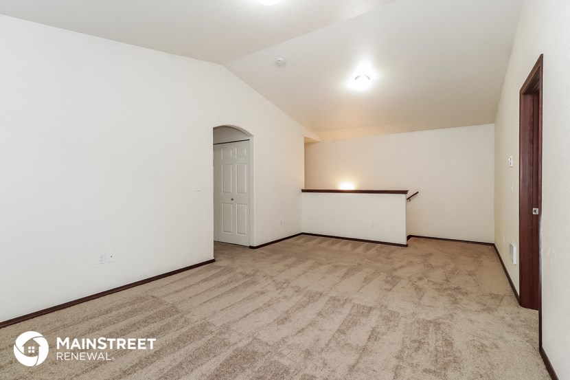 an empty living room with a door to the kitchen