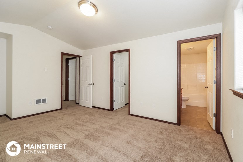 a master bedroom with a carpeted floor and three mirrors