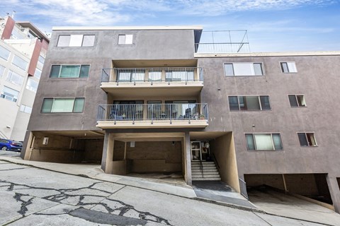 A concrete building with a balcony and stairs leading to the entrance.
