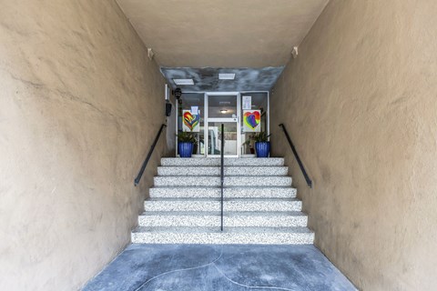 A staircase with a glass railing leading to a door with a glass window.