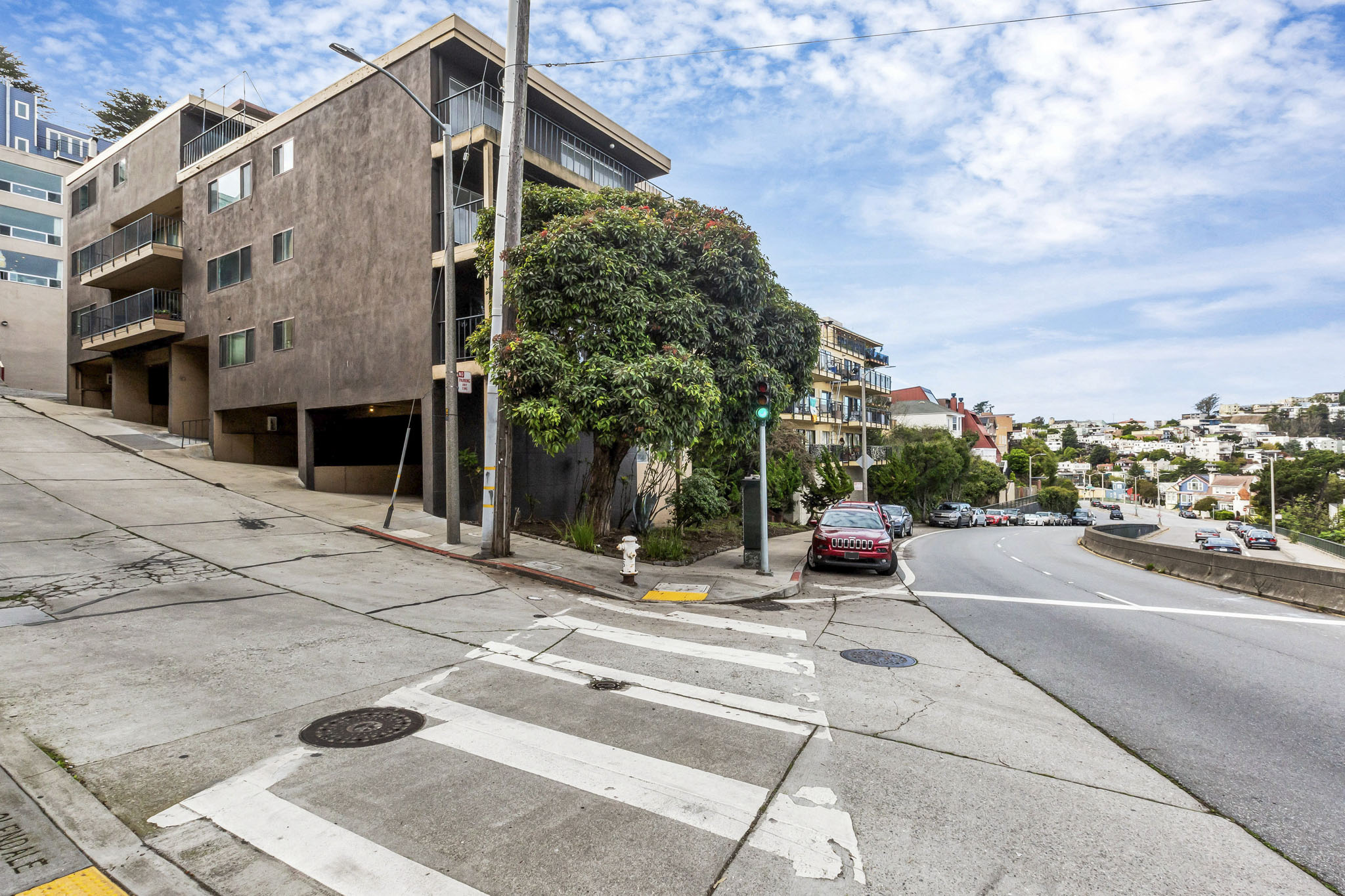 A street view with a building on the left and cars on the road.