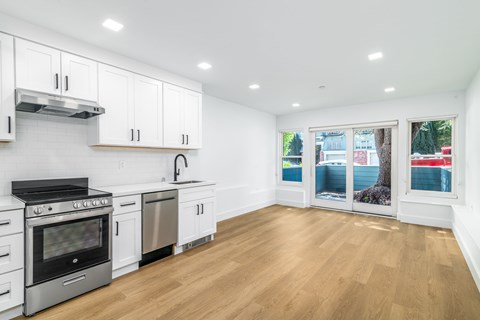 A kitchen with white cabinets and a wooden floor.