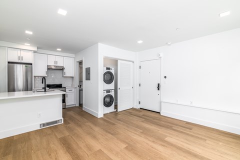 A kitchen with white cabinets and a white island with a refrigerator under it.