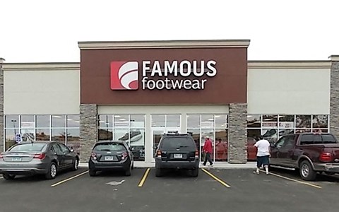 the front of a famous footwear store with cars parked in front