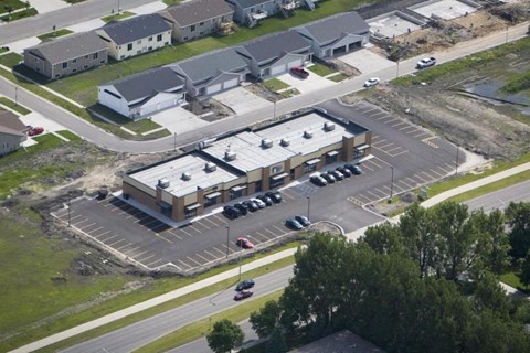 A parking lot in front of a building with cars parked.
