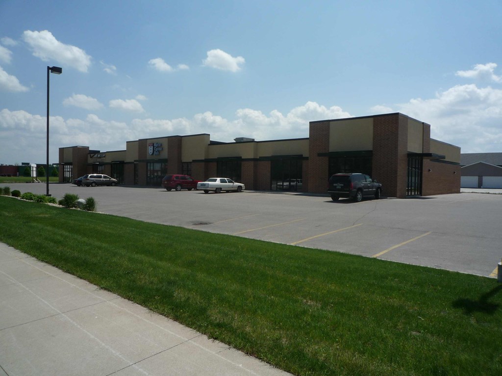 A parking lot in front of a building with cars parked.