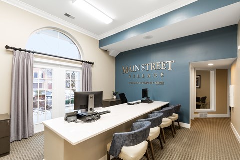 a lobby with a long desk with chairs and a large window