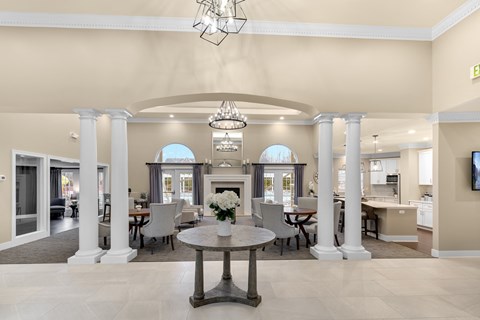 a large living room with pillars and a table with flowers