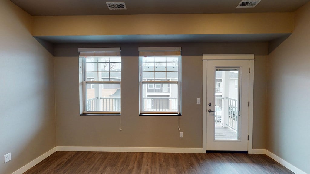 the view of a living room with a door and windows