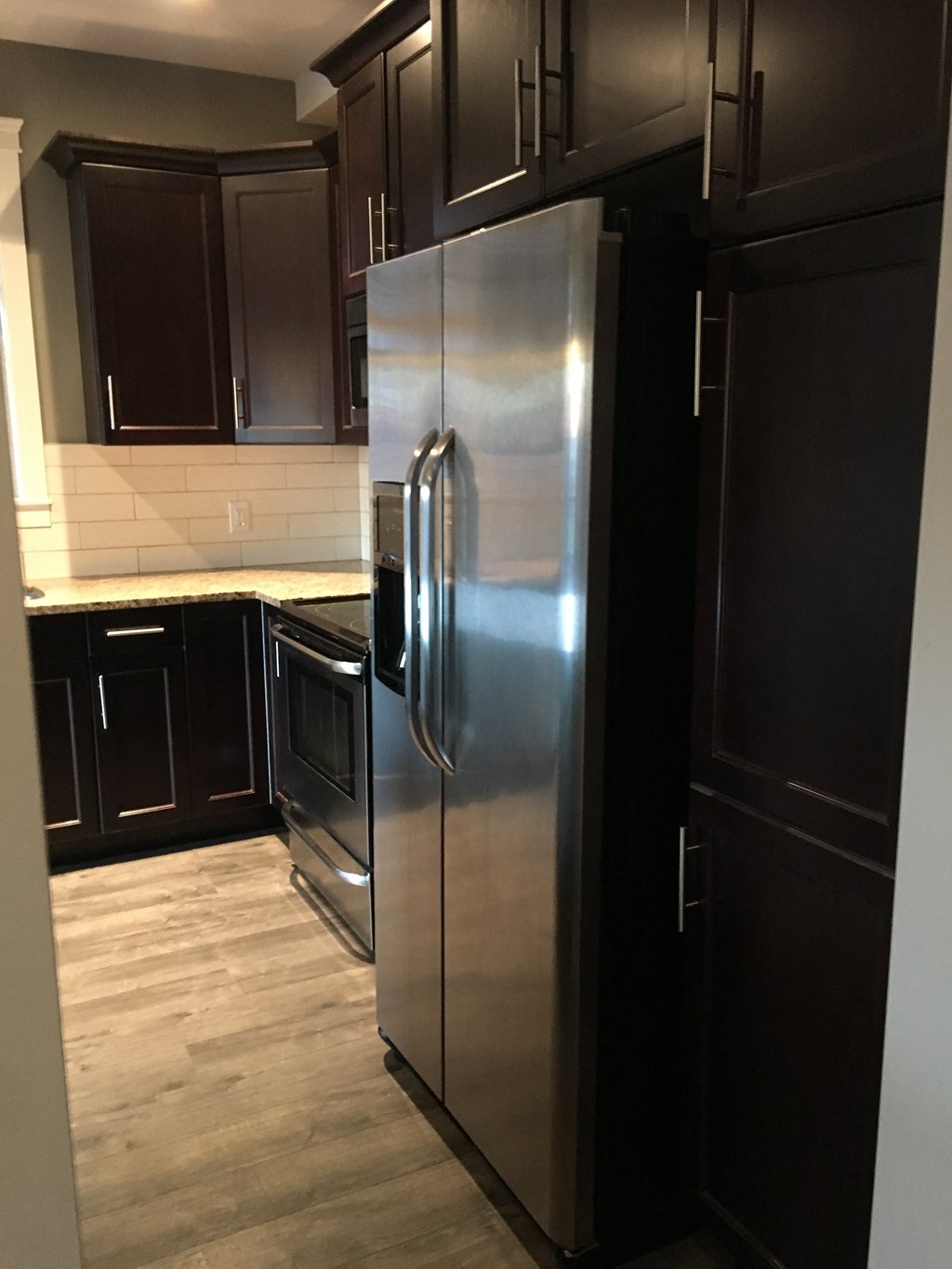 a kitchen with a stainless steel refrigerator and black cabinets