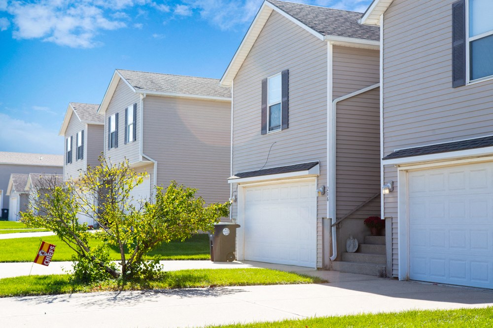 a row of houses with white garage doors and a sidewalk