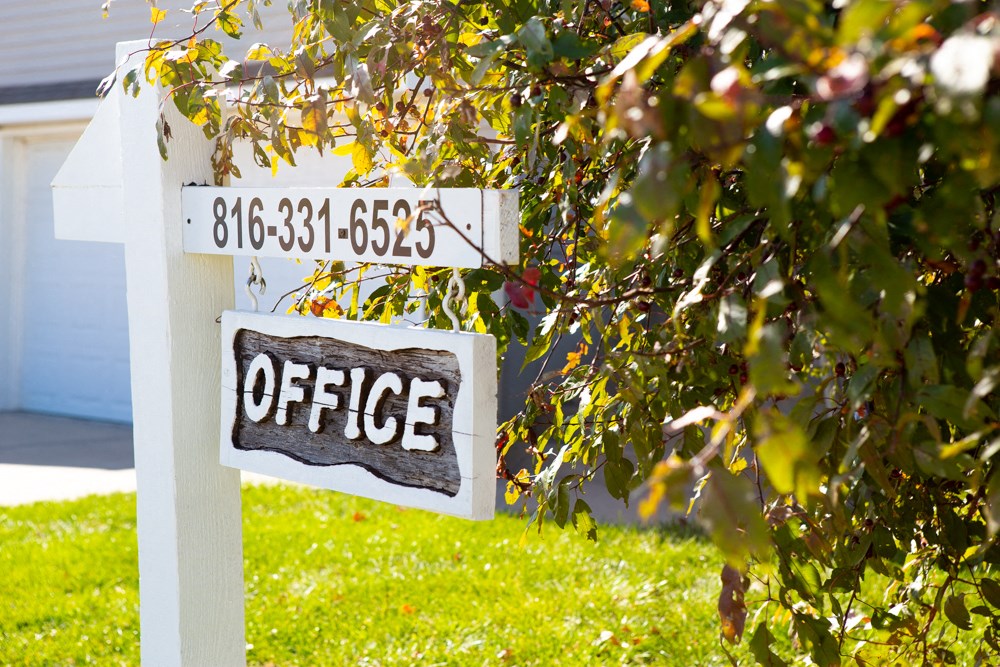 a sign for an office in front of a house
