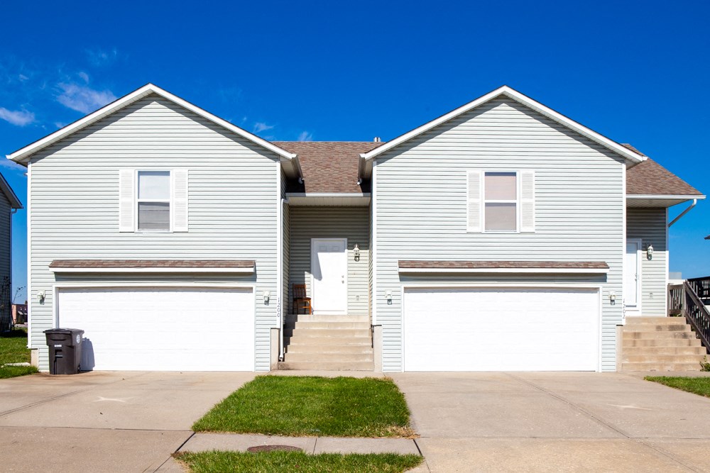 a white house with two garage doors and a driveway