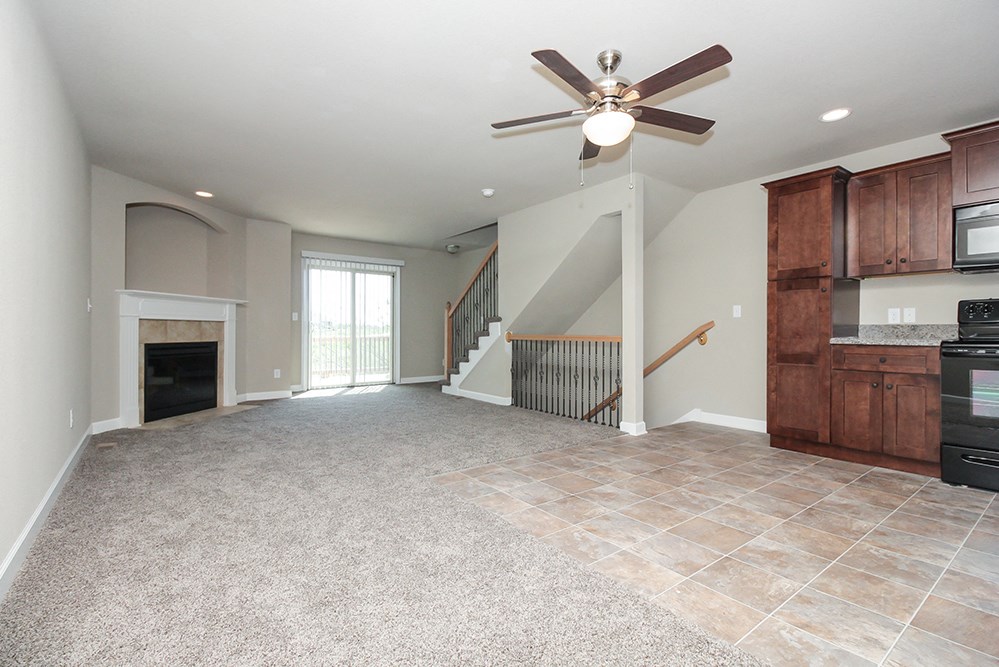 an empty living room with a fireplace and a ceiling fan